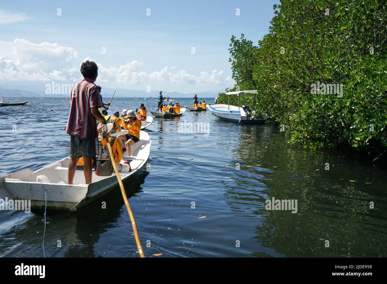 LEMBONGAN, 2. Juni 2022-Eine Gruppe von Touristen in orangefarbener Kleidung fährt mit einem traditionellen Jukung-Boot durch das ruhige Wasser des Mangrovenwaldes Stockfoto