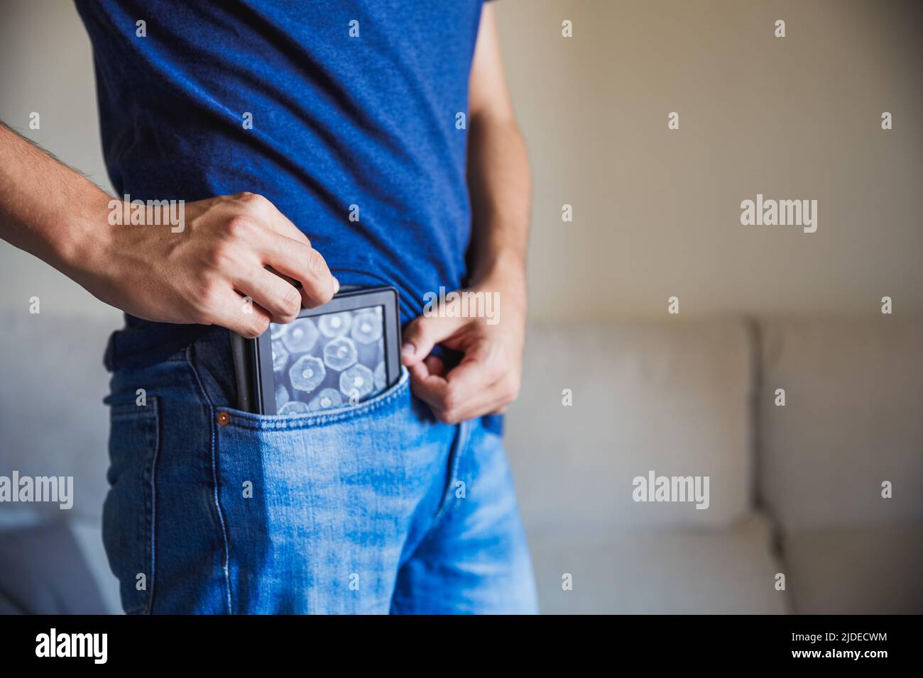 Nicht erkennbarer junger Mann, der sein eBook in seine Hosentasche steckt, Taschenbuch Stockfoto