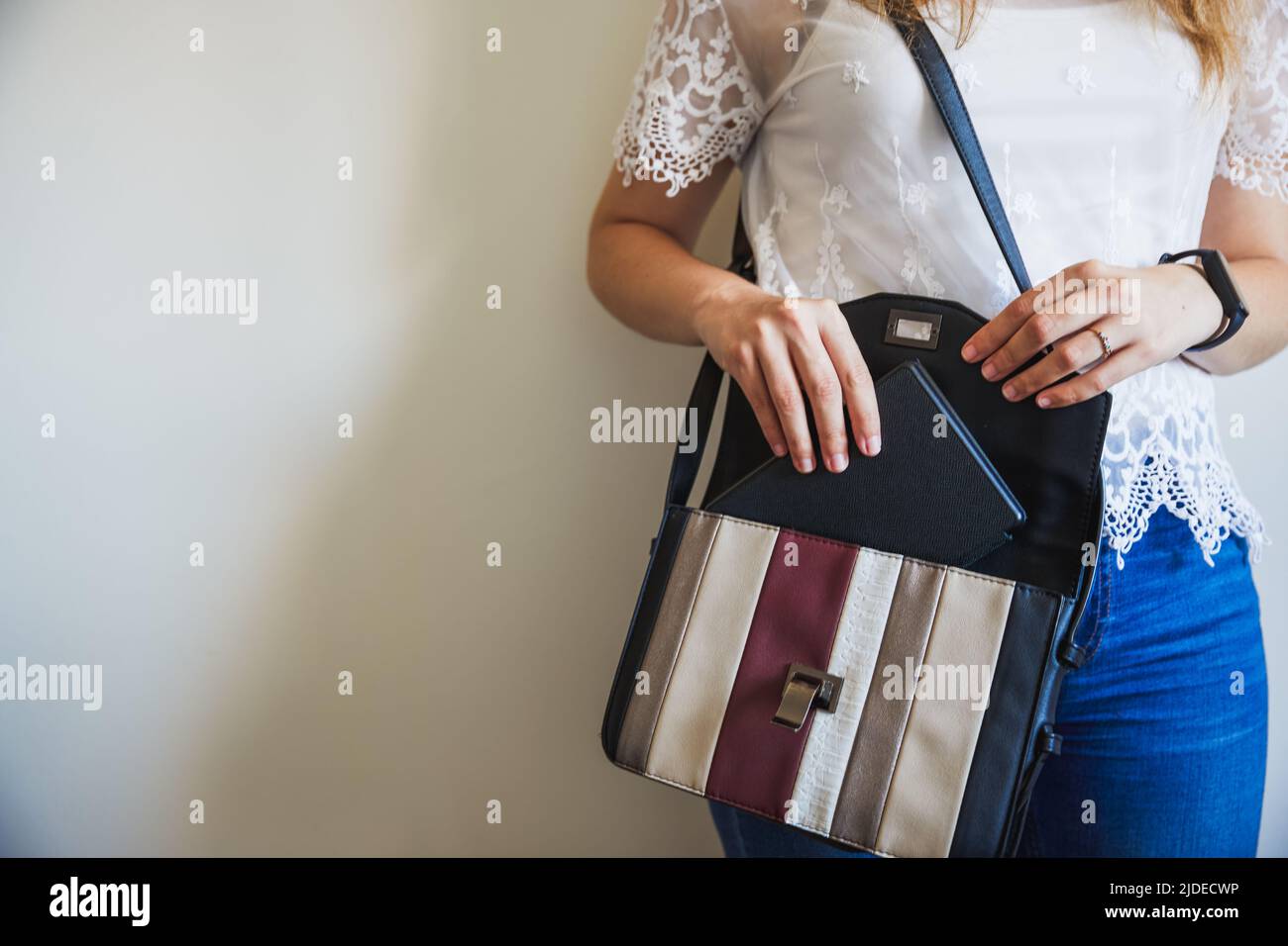 Nicht erkennbare junge Frau, die ihr eBook in ihre Handtasche, das Reisebuch, legt Stockfoto