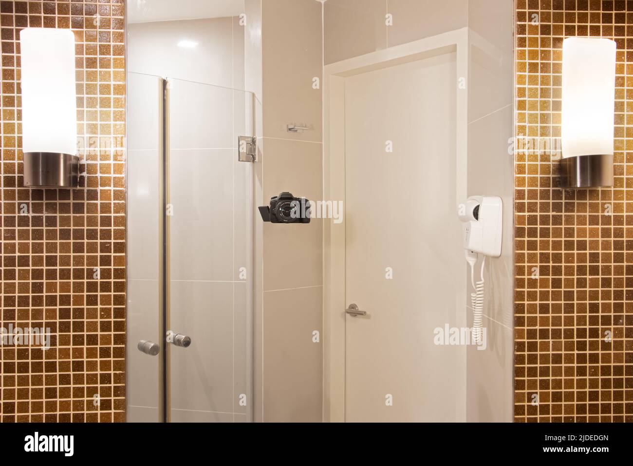 Spiegelung eines Badezimmers mit einer Kamera, die einen Spiegel fotografiert, der an der Toilettenwand hängt Stockfoto