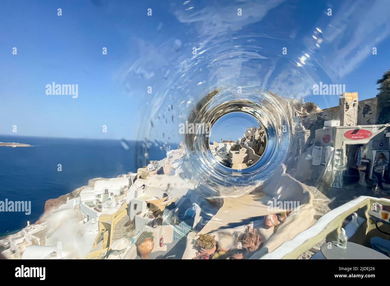 Eine seltene Ansicht des ikonischen Oia auf Santorini Insel, gesehen durch den Boden einer Wasserflasche Stockfoto
