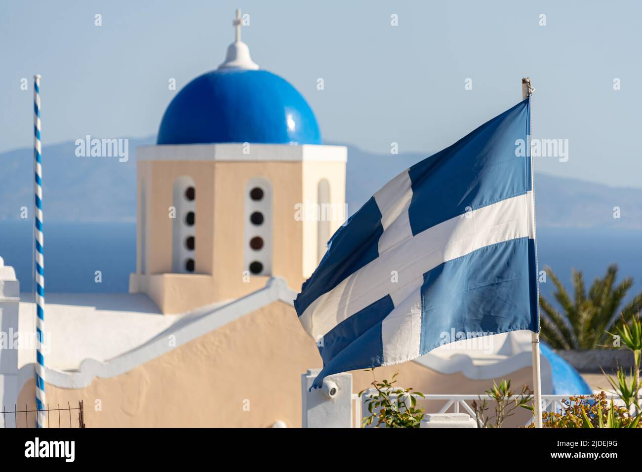 Mittlere Nahaufnahme einer blauen Kuppel mit der alten griechischen Nationalflagge im Vordergrund Stockfoto