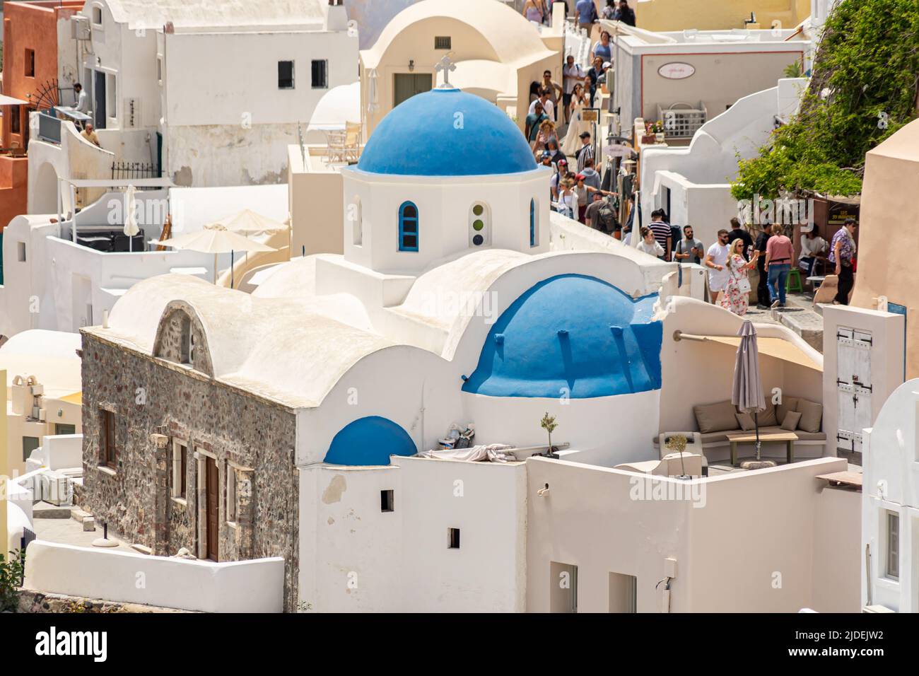 Blaue Kirchenkuppeln zwischen pastellfarbenen Stadthäusern in Oia Stockfoto