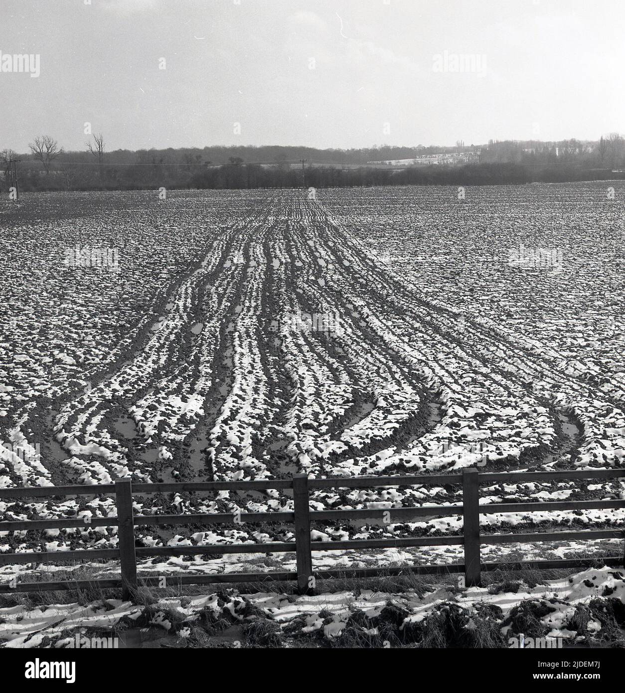 1960s, historisch, Winterzeit und auf einer Farm Blick über ein schneebedecktes Feld, wobei der gepflügte Mittelteil des Bodens ein unverwechselbares Muster macht, England, Großbritannien. Stockfoto