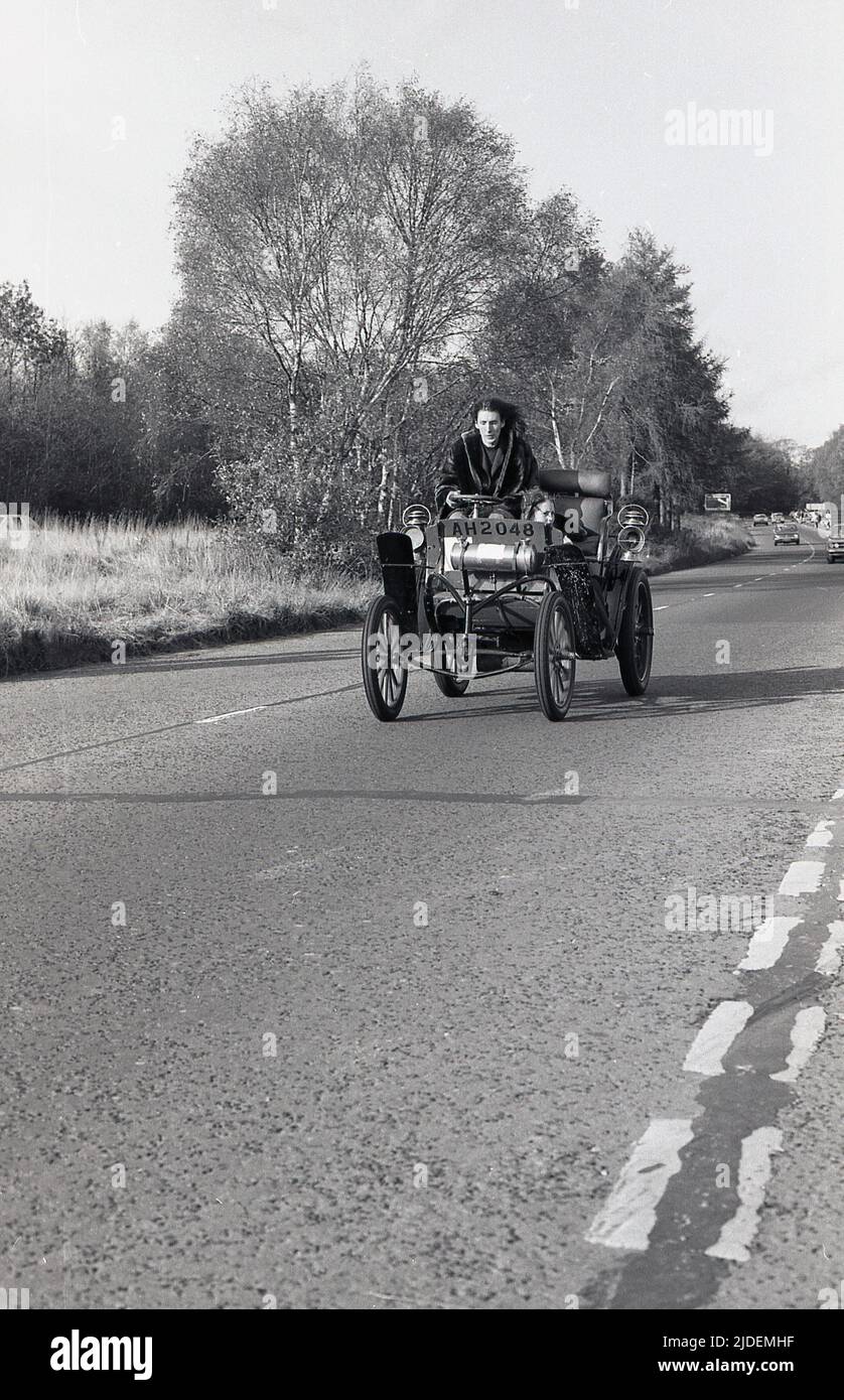 1980, historisch, ein männlicher Konkurrent mit einem kleinen Kind im Auto, das an der Oldtimer-Rallye teilnahm, London nach Brighton. Der Oldtimer mit offenem Oberdeck hat das Kennzeichen AH 2048. Stockfoto