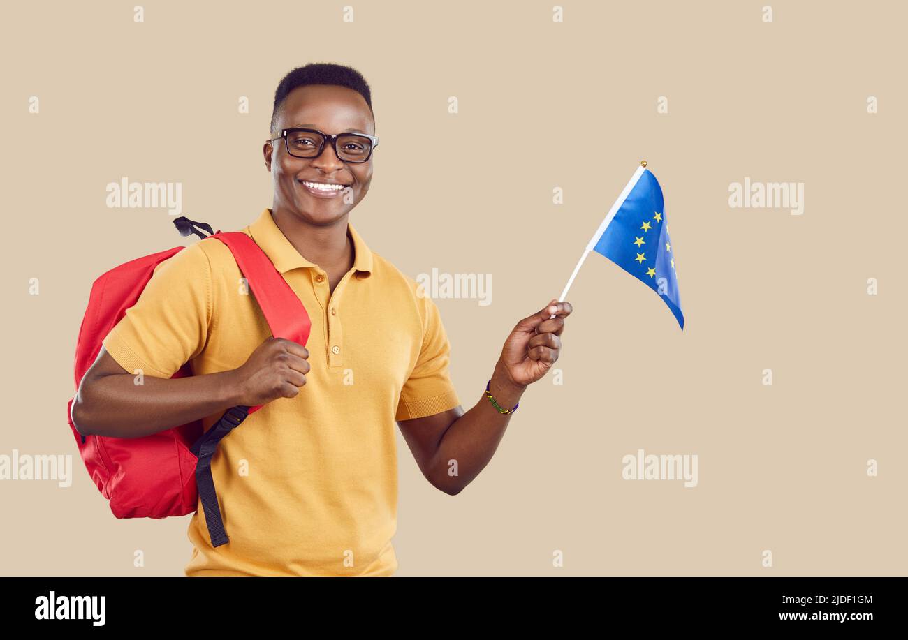 Fröhlicher afroamerikanischer Student mit europäischer Gewerkschaftsflagge auf hellbeigem Hintergrund. Stockfoto