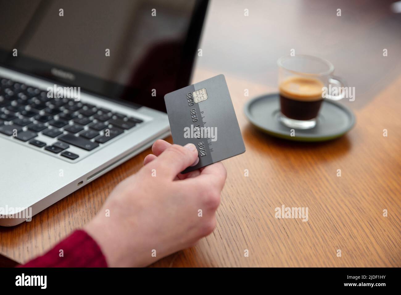Hände mit Plastikkreditkarte und Laptop, Holztisch Hintergrund, Nahaufnahme. Online-Shopping-Konzept Stockfoto