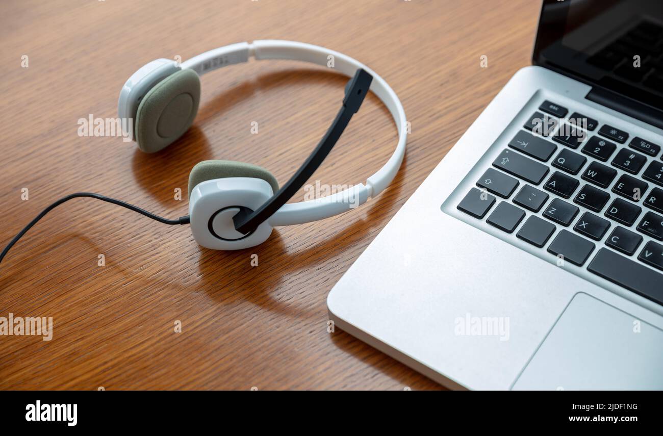 Call Center, Home Office, Kundendienst, Helpdesk-Konzept. Headset und Laptop auf einem Holztisch, Blick von oben. Stockfoto