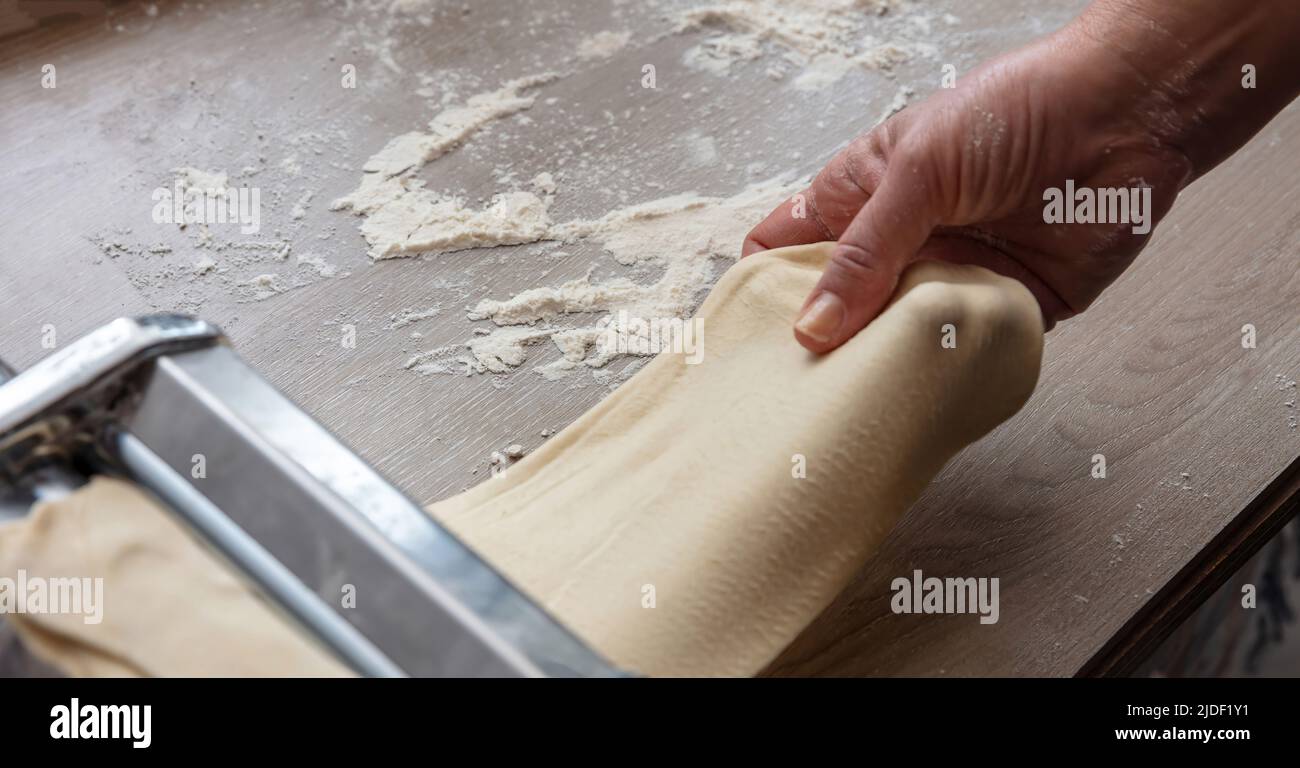 Pasta-Maschine. Frische Pasta hausgemachte Zubereitung. Männliche Hand macht Teig phylo Nahaufnahme Stockfoto