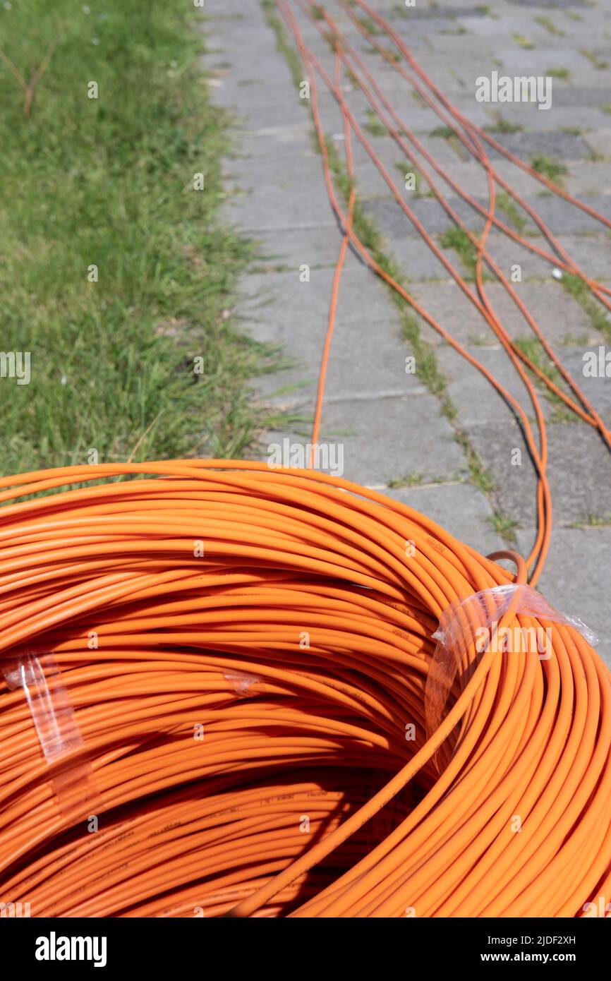Ein Paket aus gewickelten orangefarbenen Glasfaserkabeln auf der Straße, die bereit sind, in den Boden zu gelangen. Schnelles Internet. Fokus vorne Stockfoto