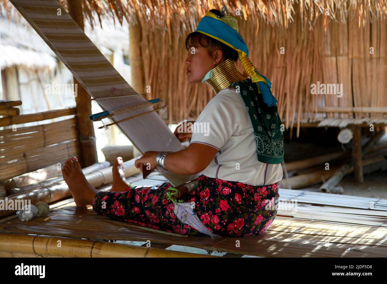 Huai seau Tao, Thailand - 04 2012. August: Junge Frau des Kayan Lahwi Stammes webt einen weißen und goldenen Schal. Stockfoto