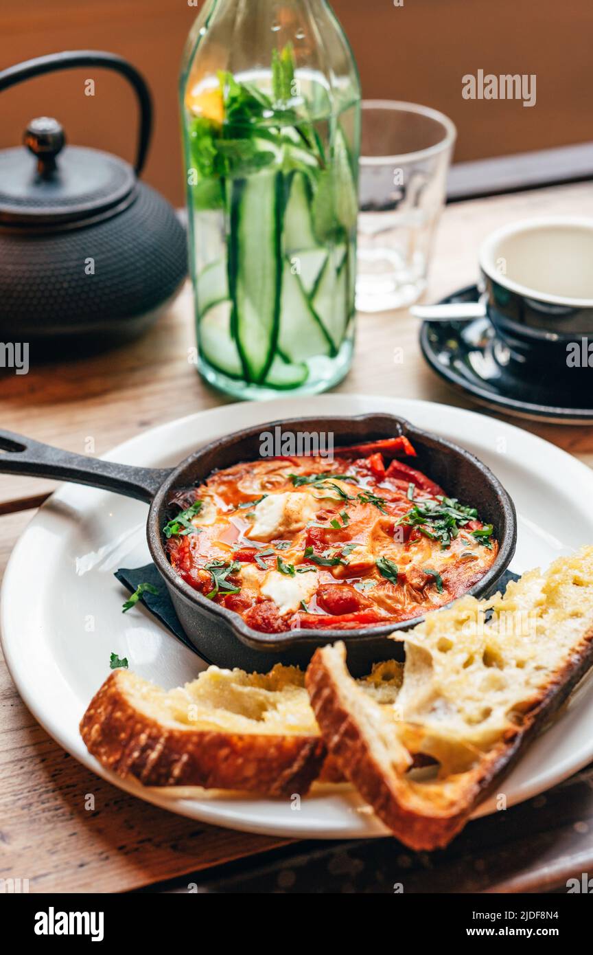 Shakshuka in eiserner Pfanne mit Brot serviert Stockfoto