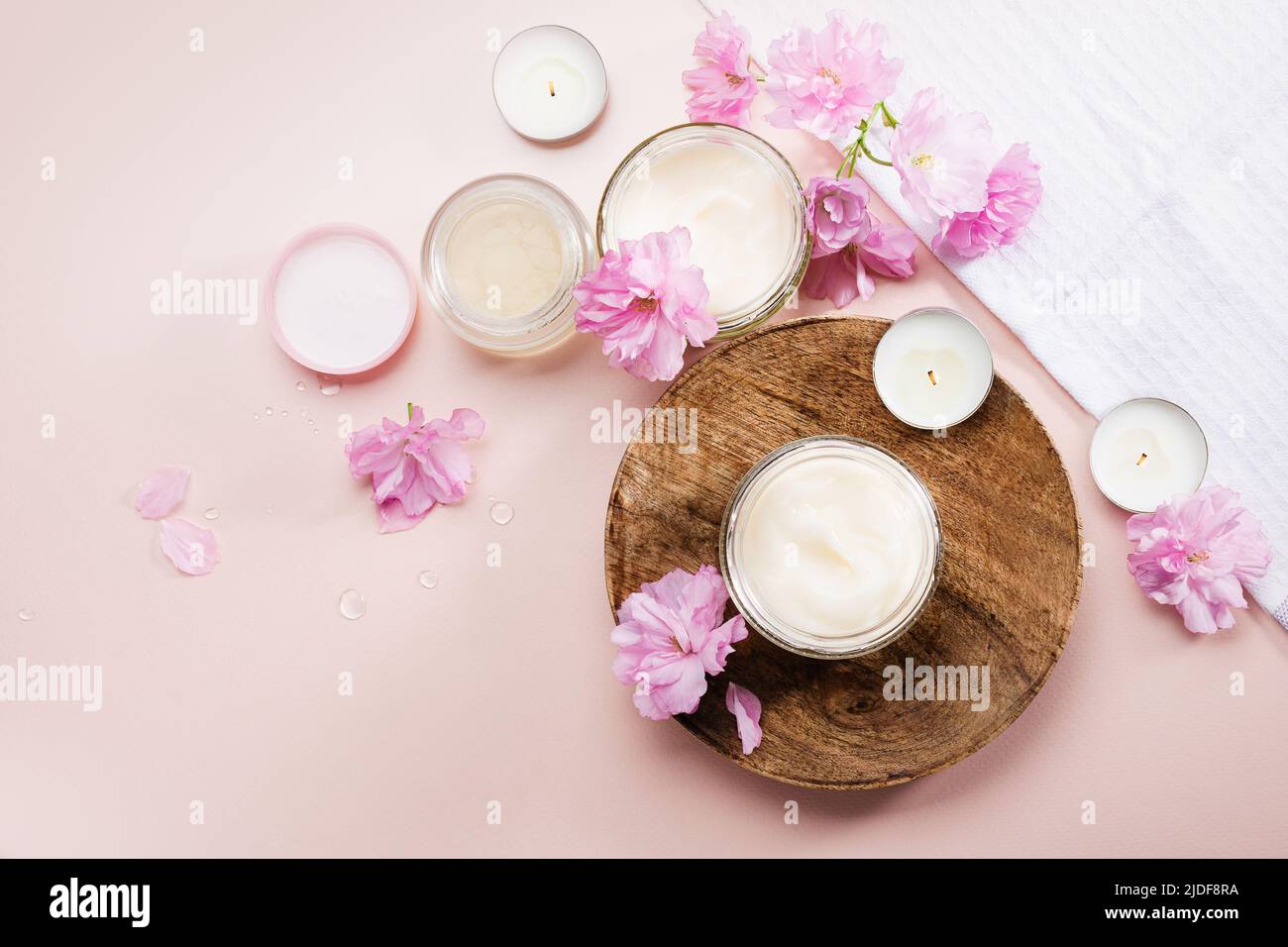 Körperpflegecreme und rosa Kirschblüten. Flach liegend. Stockfoto