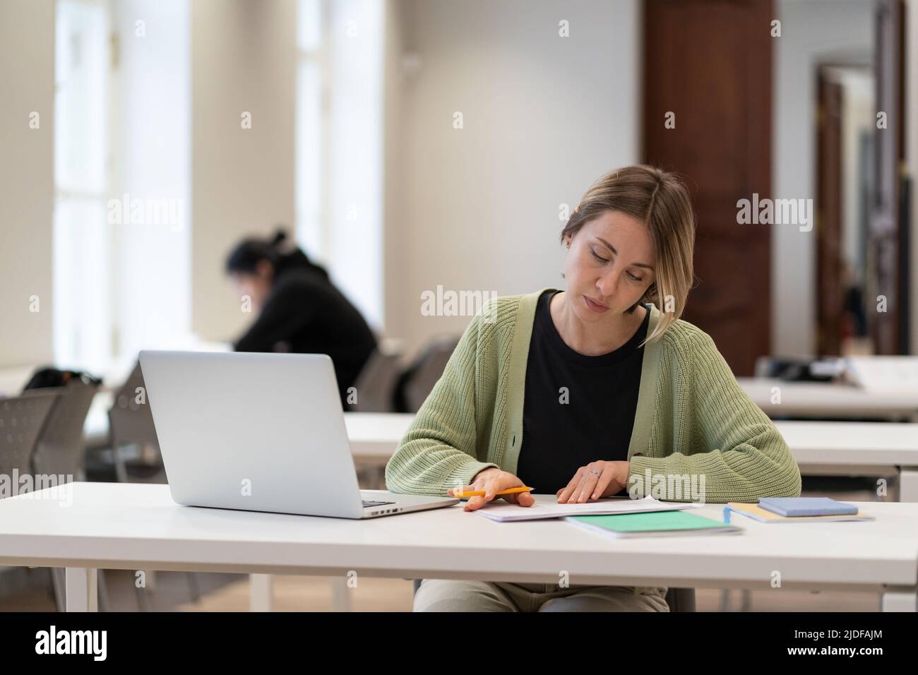 Eine fokussierte Schülerin mittleren Alters bereitet sich auf die Kursarbeit in der Hochschule oder auf dem College-Campus vor Stockfoto