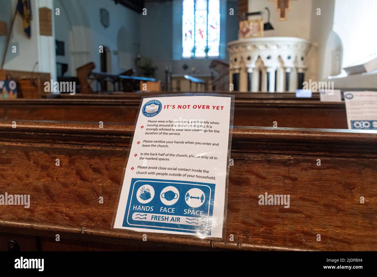 Schild mit der Aufschrift „Es ist noch nicht vorbei“ in einer Kirche über die covid-19-Pandemie im Jahr 2022, auf der die Menschen aufgefordert werden, weiterhin Gesichtsbezüge oder Masken zu tragen Stockfoto