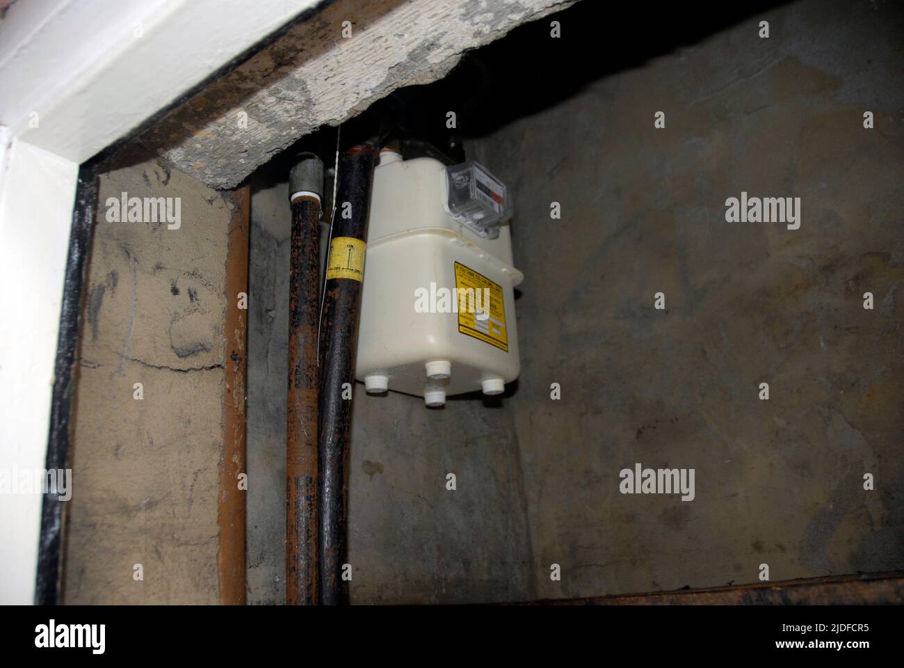 Herkömmlicher Gaszähler in einer ungünstigen Position hoch oben in einem kleinen Schrank im Freien Stockfoto