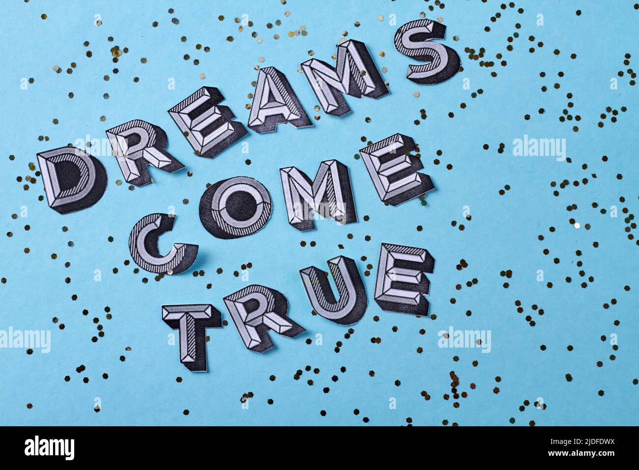 Träume werden wahr Schriftzug Inschrift mit Pailletten. Isoliert auf blauem Hintergrund. Stockfoto
