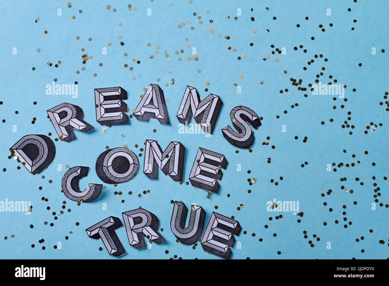 Träume werden wahr Inschrift Schriftzug mit Pailletten. Isoliert auf blauem Hintergrund. Stockfoto
