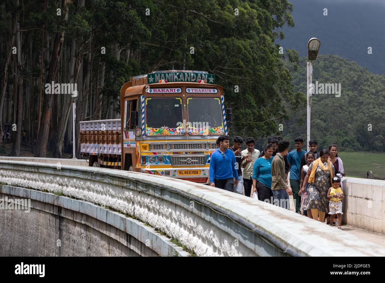 Touristen, die in der Mitte spazieren, blockieren den Weg eines LKWs auf der Kundalai Road, die über den Kundala-Staudamm führt Stockfoto