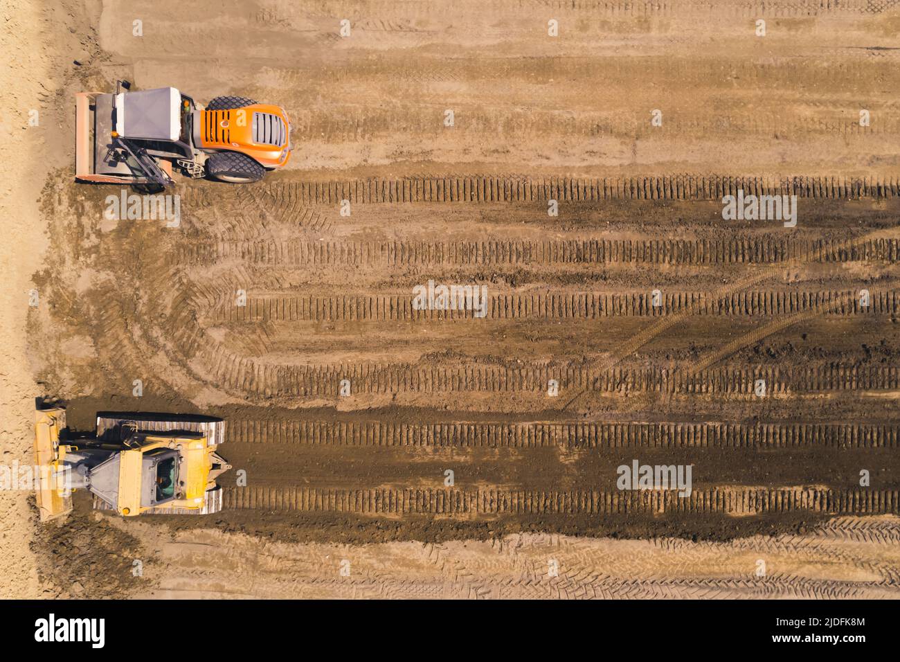 Straßenbaustelle für eine neue Autobahn. Zwei schwere Industriemaschinen, die durch losen Sand fahren und Spuren hinterlassen. Hochwertige Fotos Stockfoto