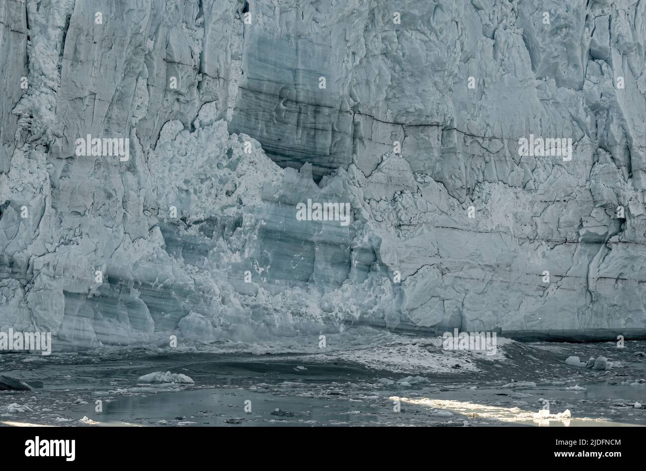 Disenchantment Bay, Alaska, USA - 21. Juli 2011: Nahaufnahme eines blau-weißen Hubbard-Gletscherwandstücks, das im Meerwasser versinkt und Wellen erzeugt. Stockfoto