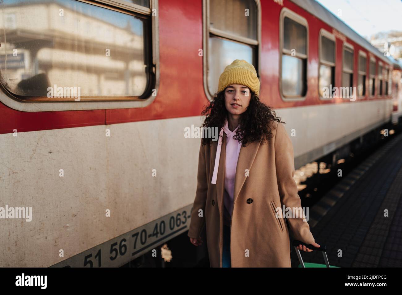 Junge Reisende Frau mit Gepäck, das auf dem Bahnsteig stand und in den Zug steigen Stockfoto