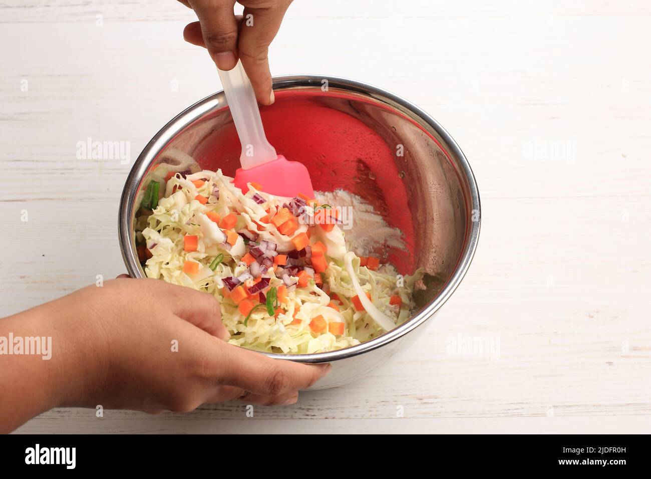 Asiatische weibliche Hand Mischen Sie Gemüse, mit Mehl auf Edelstahl Schüssel mit Spatel. Kochvorgang Zubereitung von Gemüsefrittern (Bala bala oder OTE-ote oder Pakora Stockfoto