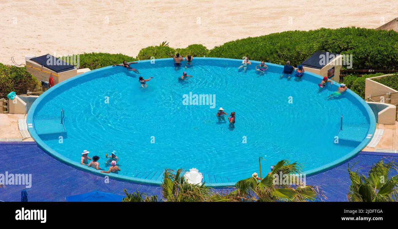 Leute im Hotel rund um den randlosen Pool am Strand in Cancun, Mexiko Stockfoto