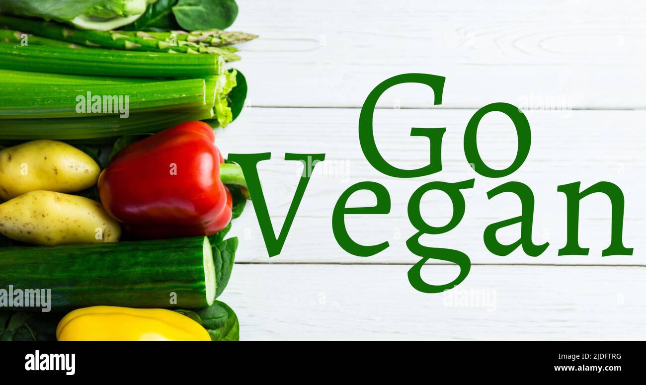Bild von GO vegan Text in grün über frischem Gemüse auf weißen Brettern Stockfoto