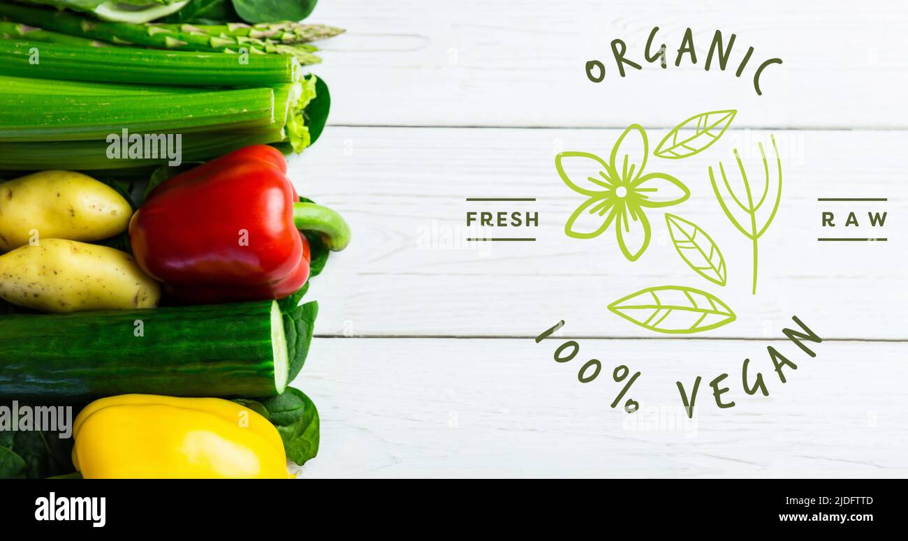 Bild von Bio 100 Prozent veganer Text in grün, über frischem Gemüse auf weißen Brettern Stockfoto