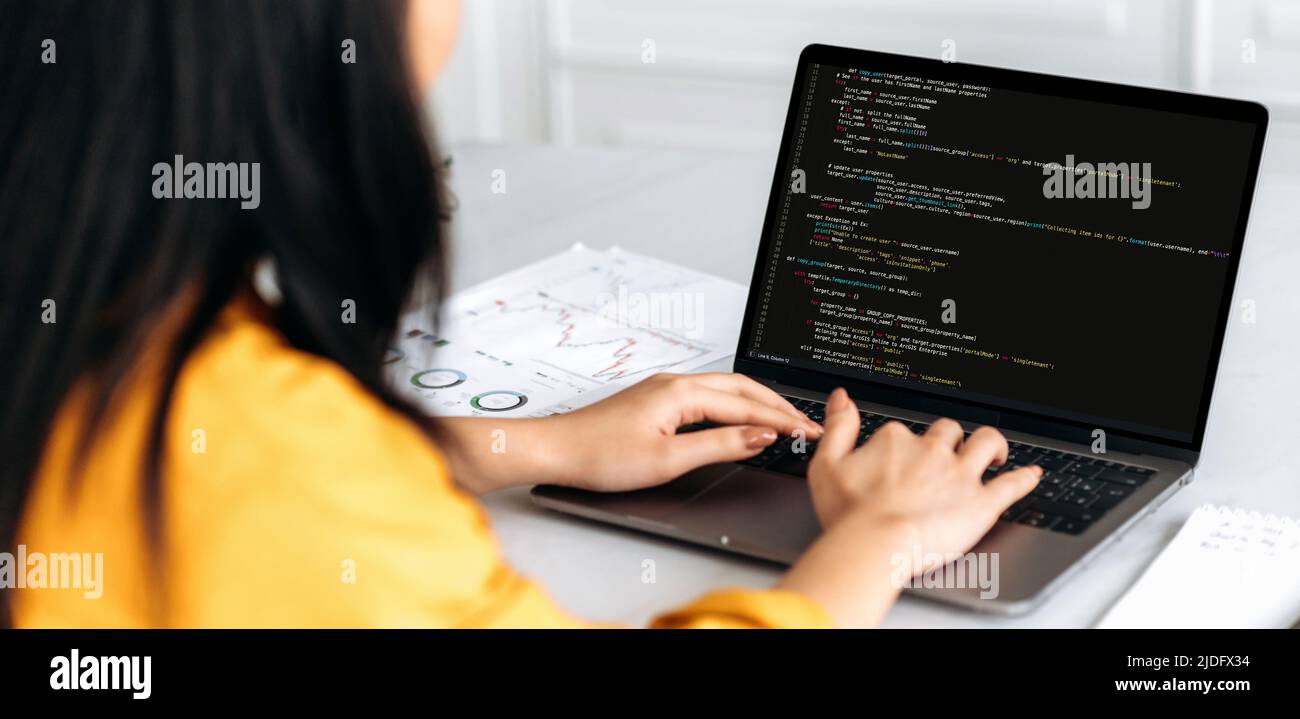 Panorama über die Schulter Blick weibliche IT-Spezialisten auf einen Laptop mit Programmiercode auf dem Bildschirm. Intelligente professionelle Programmiererin, die mit einer Software und Codierungstechnologie arbeitet und Codes schreibt Stockfoto