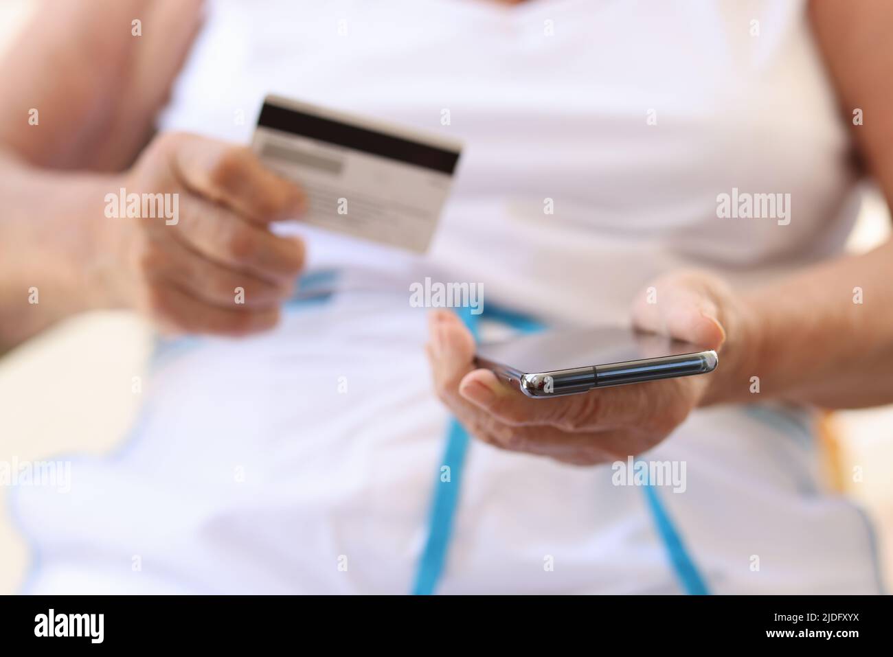 Nahaufnahme einer alten Frau, die Mobiltelefon und Bankkarte in den Händen hält. Ältere Frauen, die elektronische Zahlungen leisten. Pensionsfonds- und Zahlungskonzept Stockfoto
