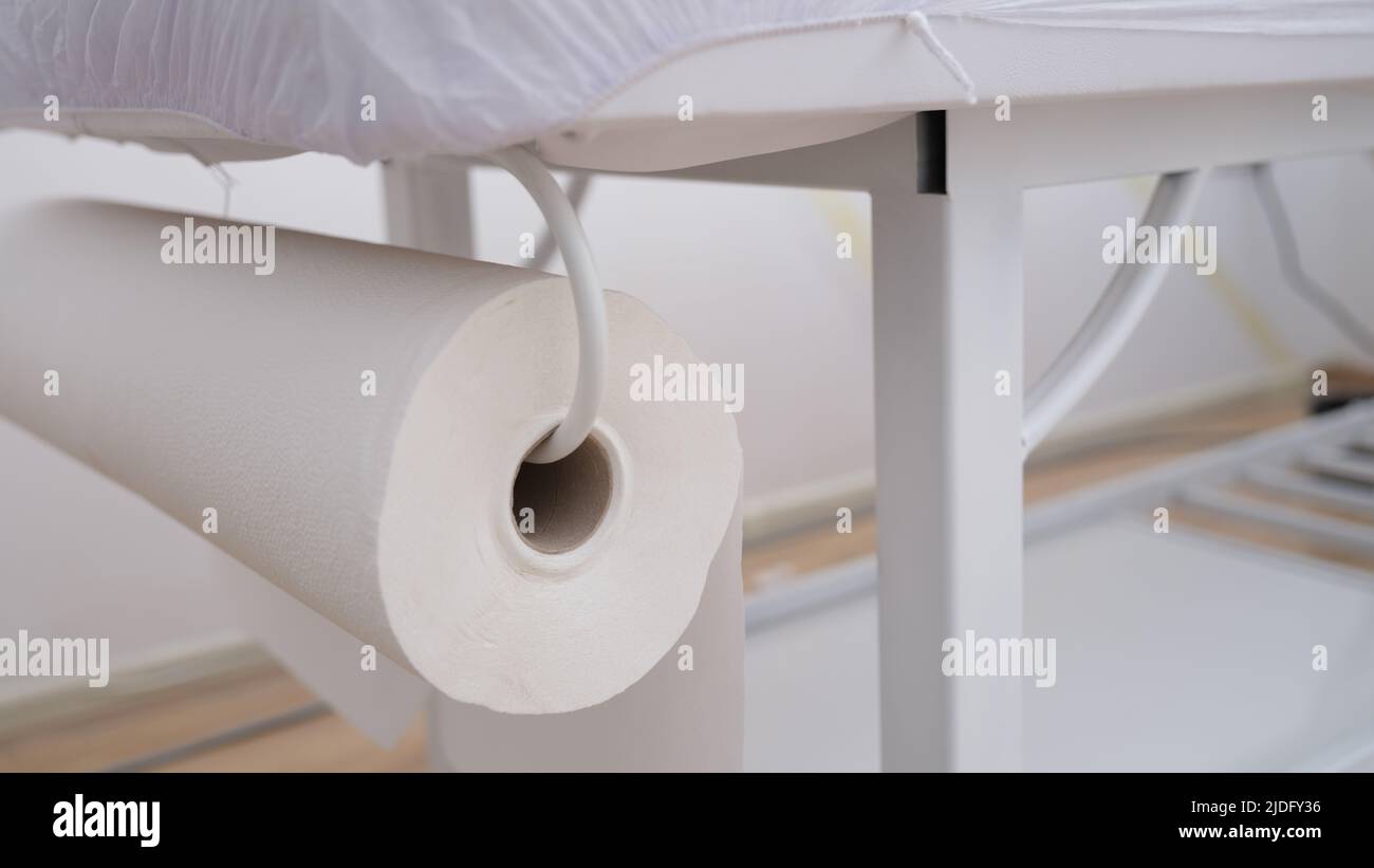 Nahaufnahme einer großen Rolle Servietten, die auf der Couch befestigt sind. Massage- oder Manipulationsraum. Sonderausrüstung, Werkzeuge und Verbrauchsmaterialien Stockfoto