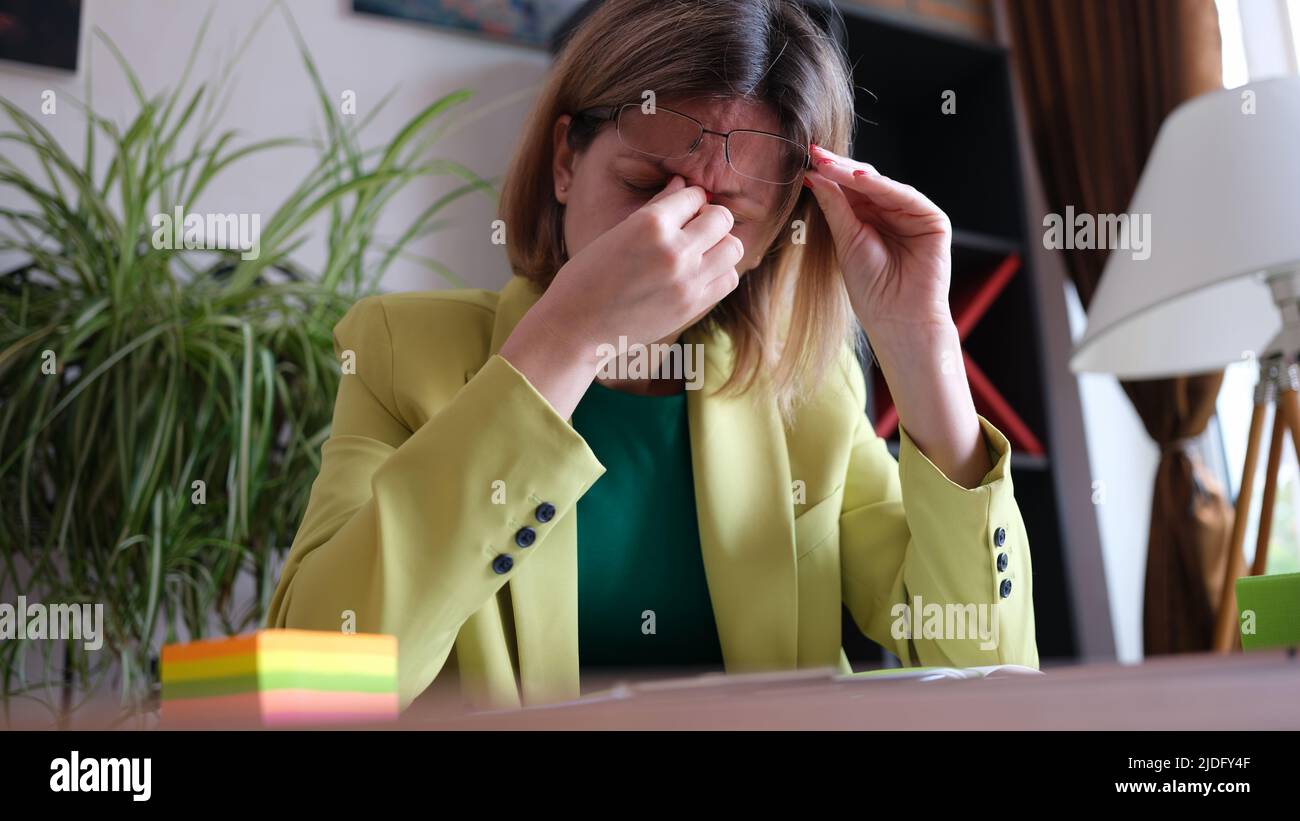Überarbeitete Frau, die am Arbeitsplatz im Büro sitzt Stockfoto