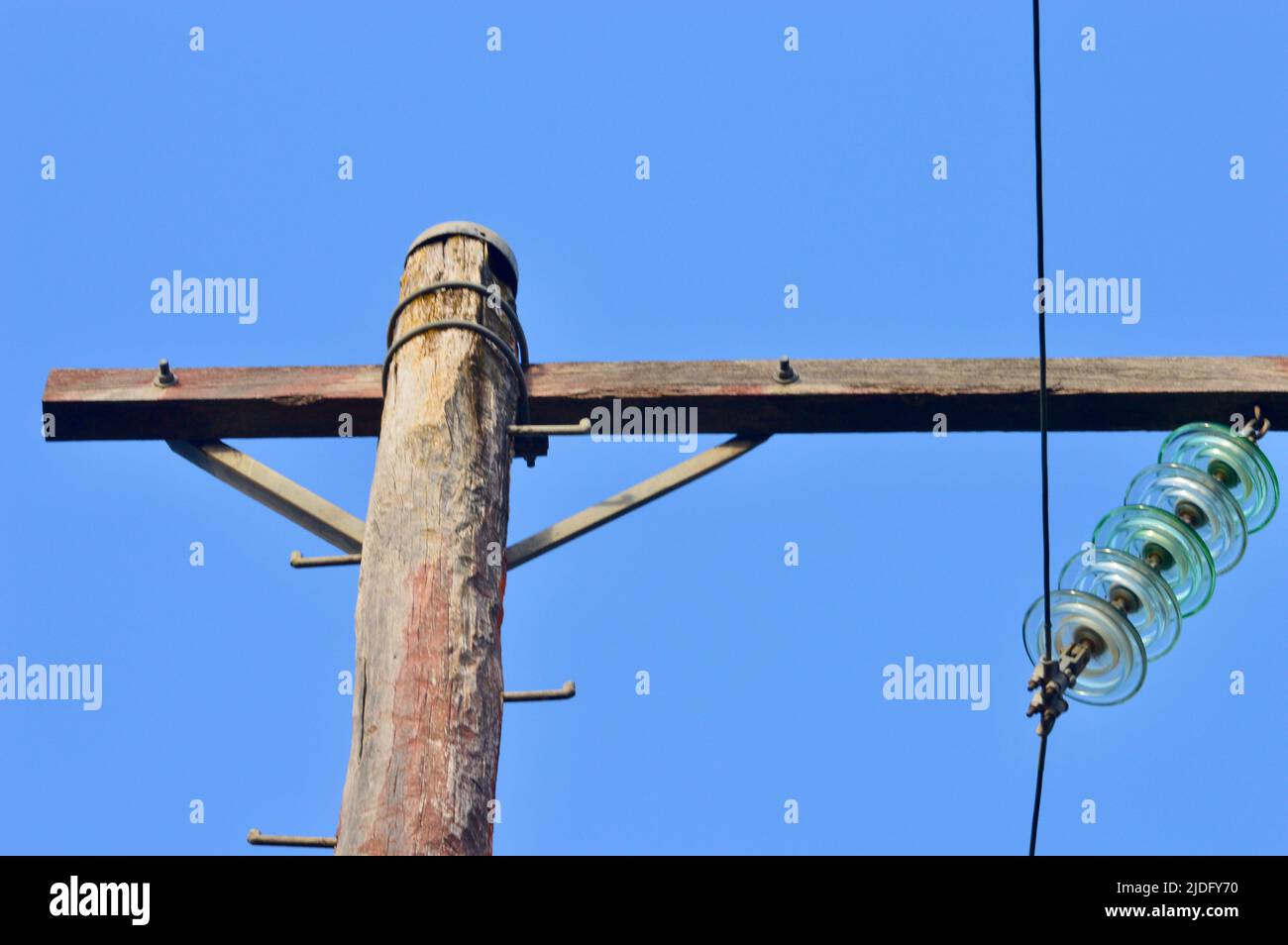 Ein hölzerner Strommast gegen einen blauen Himmel Stockfoto