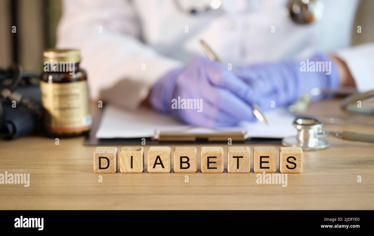 Nahaufnahme des Diabeteswortes mit Holzwürfeln in Reihe. Arzt Endokrinologe schreiben Rezept. Diagnose und Behandlung von Diabetes mellitus Stockfoto