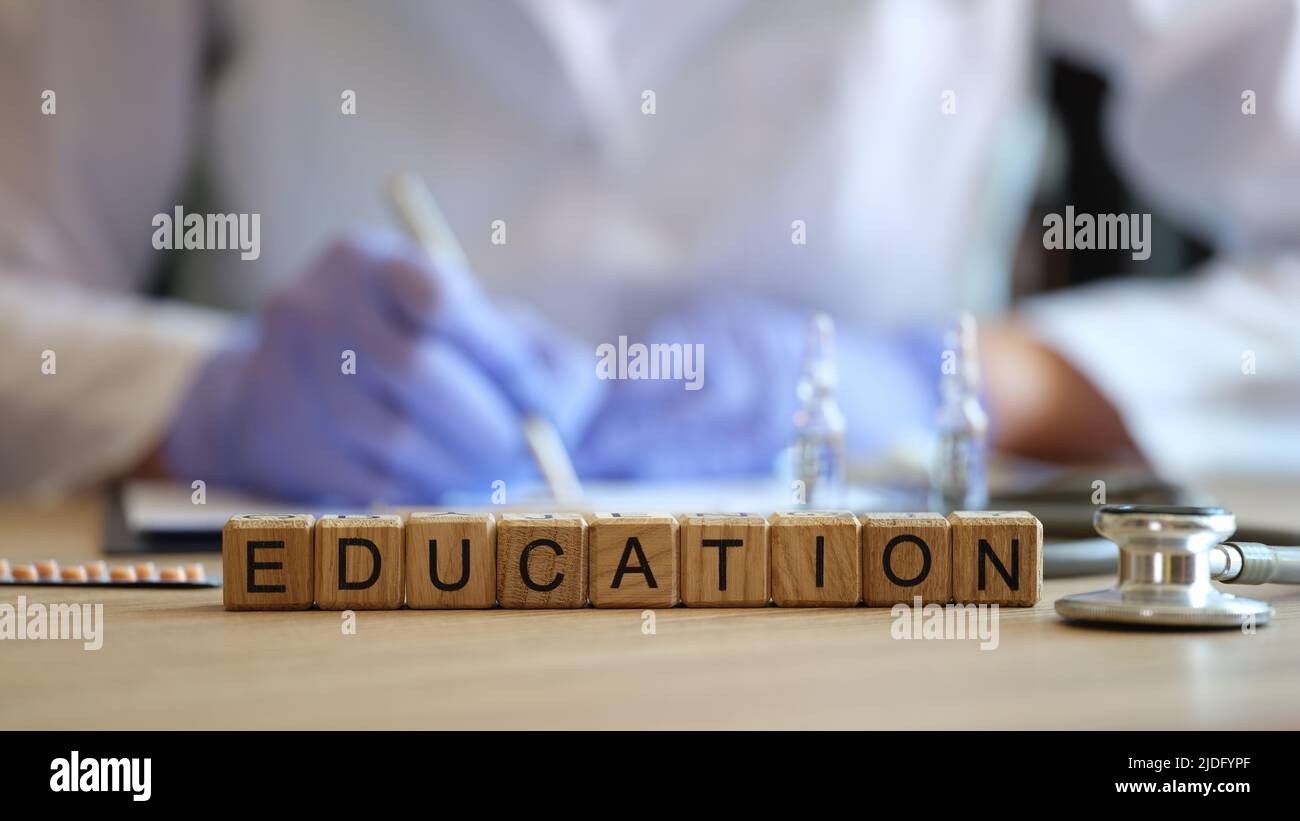 Nahaufnahme der Worterziehung, die von Holzwürfeln in rohem Holz gesammelt wurde. Arzt in medizinischen Uniform schriftlich Informationen. Medizinisches Bildungskonzept Stockfoto