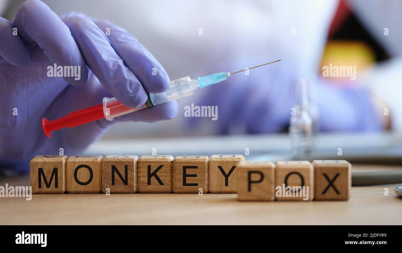 Nahaufnahme der Wörter, die aus Holzwürfeln gesammelte Affenpocken. Krankenschwester hält Injektionsspritze in der Hand. Viruserkrankung, Impfstoff und Impfkonzept Stockfoto