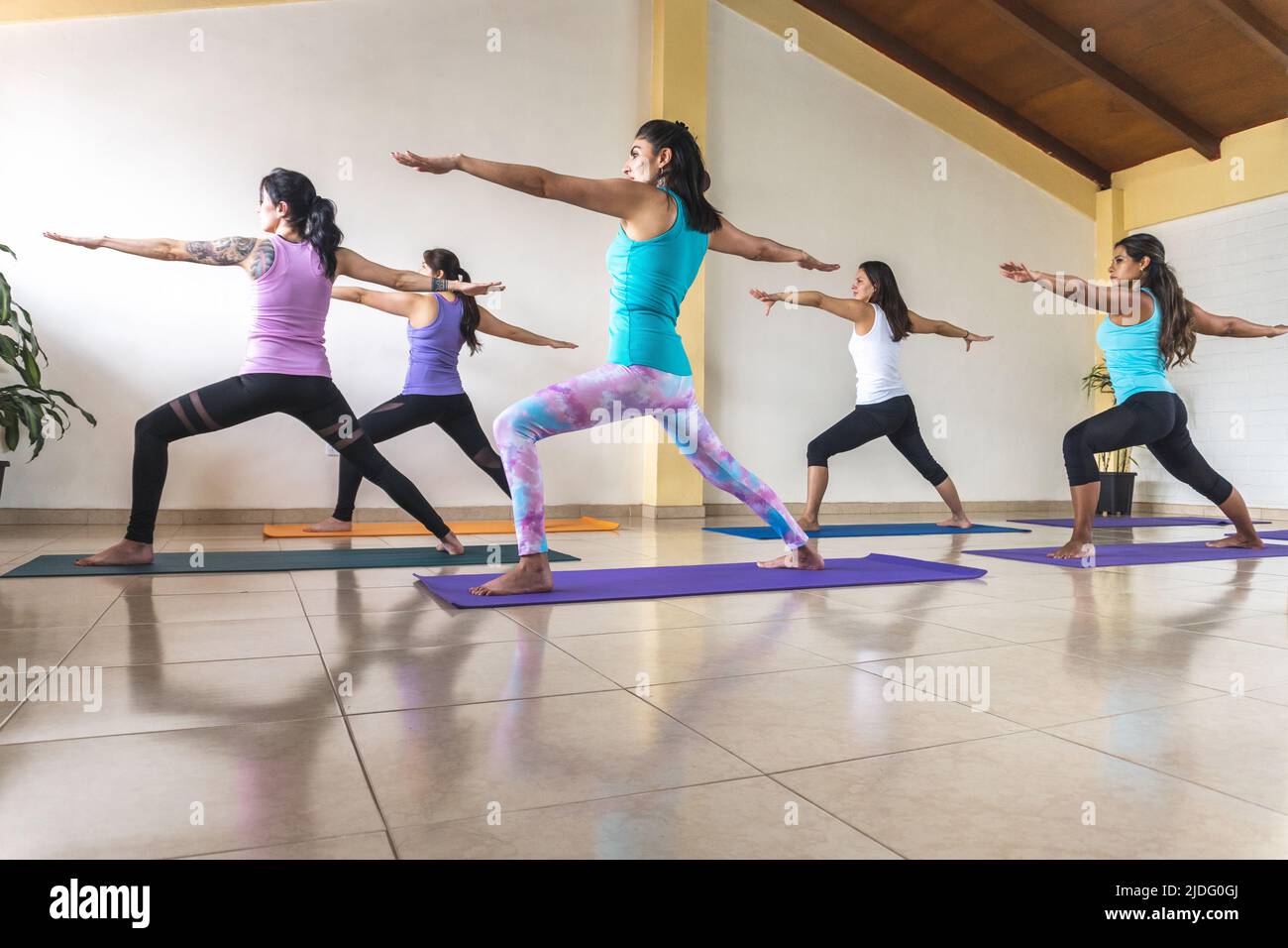 Gruppe von Frauen, die Yoga in Kriegerposition oder Virabhadrasana praktizieren Stockfoto