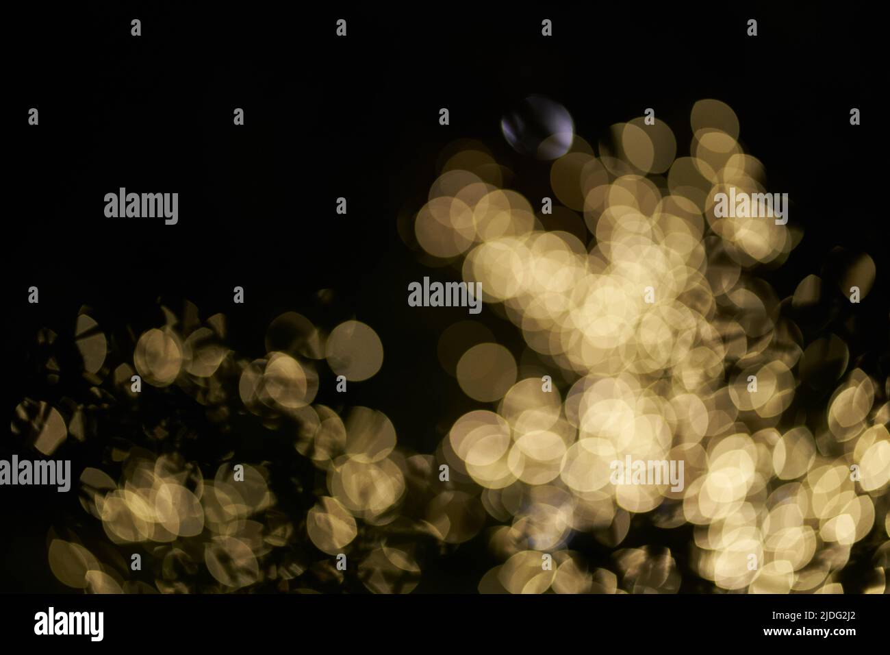 Verschwommenes, glühendes Bokeh-Licht auf schwarzem Hintergrund hervorgehoben. Festlicher goldener, leuchtender Hintergrund mit gelben Lichtern. Overlay Bokeh für Ihr Design. Hochwertige Fotos Stockfoto