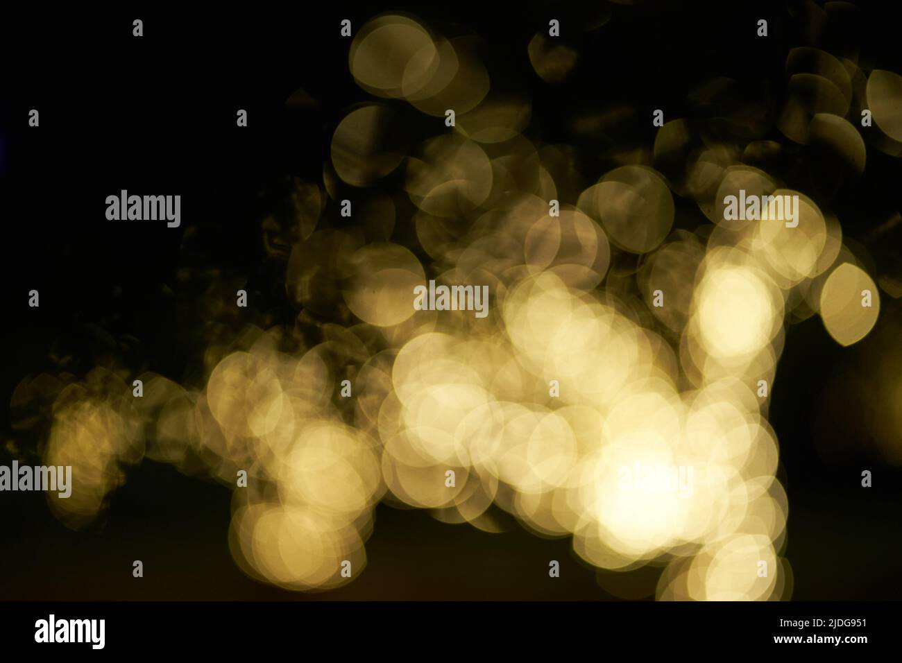 Verschwommenes, glühendes Bokeh-Licht auf schwarzem Hintergrund hervorgehoben. Festlicher goldener, leuchtender Hintergrund mit gelben Lichtern. Overlay Bokeh für Ihr Design. Hochwertige Fotos Stockfoto