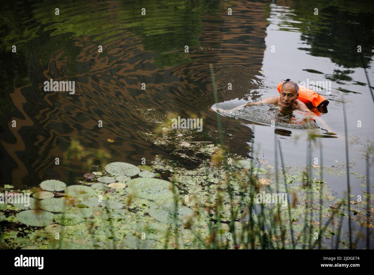 Ein Mann schwimmt an einem heißen Tag der Sommersonnenwende in Peking, China, am 21. Juni 2022 in einem Kanal. REUTERS/Thomas Peter Stockfoto