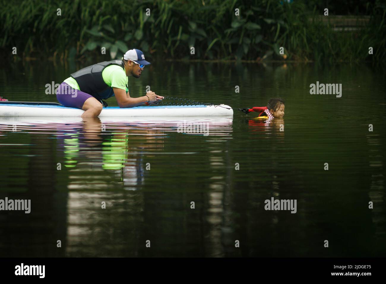 Ein Mann hilft einem Mädchen, während sie an einem heißen Tag der Sommersonnenwende in Peking, China, in einem Kanal schwimmt, 21. Juni 2022. REUTERS/Thomas Peter TPX-BILDER DES TAGES Stockfoto
