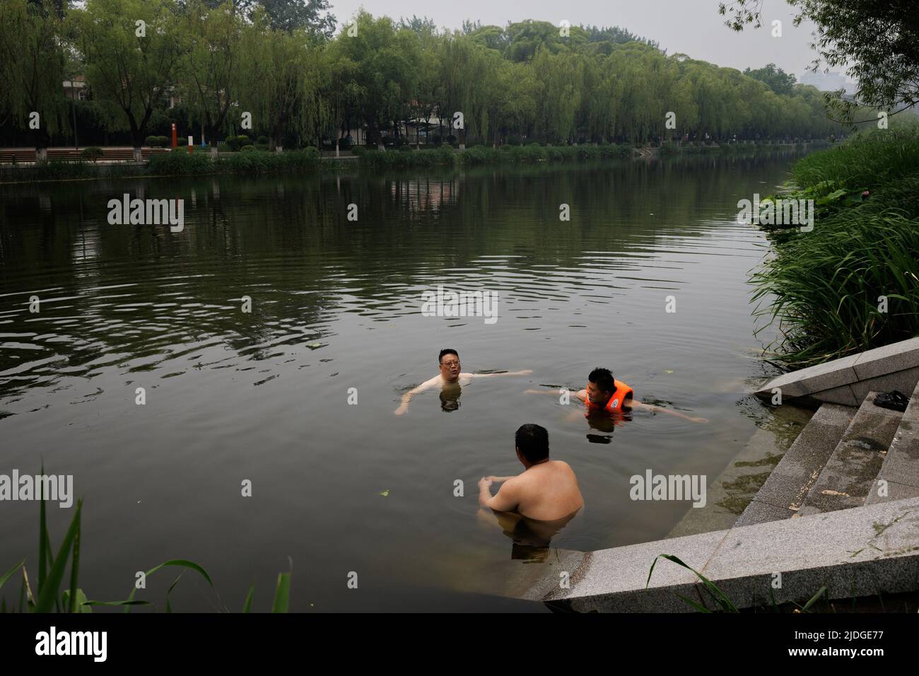 Männer schwimmen an einem heißen Tag an der Sommersonnenwende in Peking, China, am 21. Juni 2022 in einem Kanal. REUTERS/Thomas Peter Stockfoto