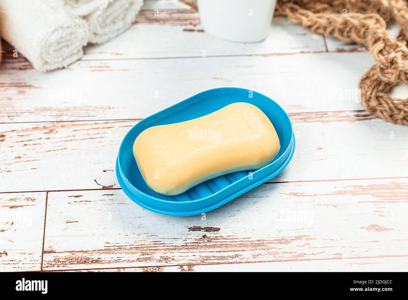 Seife auf einer blauen Seifenschale isoliert auf einem Holztisch. Hygiene Sauberkeit Reisekonzept Stockfoto