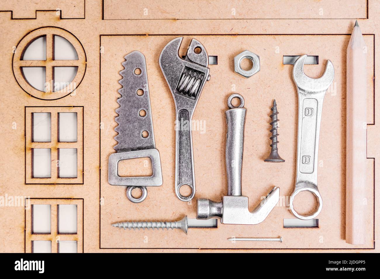 Set von Miniatur-Tools und Befestigungselementen, um ein Haus auf einem hölzernen Haus Modell-Kit angeordnet zu bauen. Stockfoto