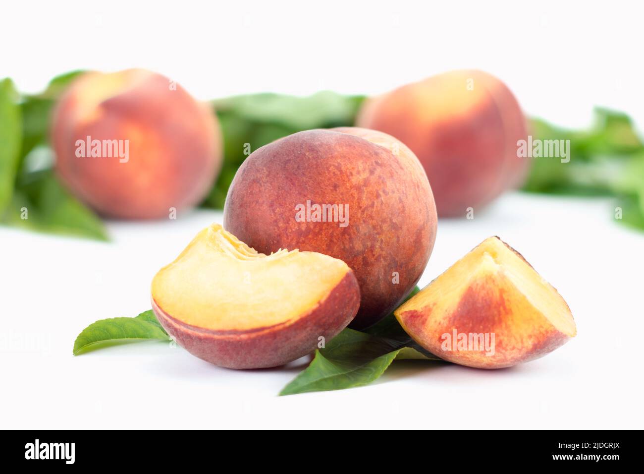 Frische reife Pfirsiche Früchte mit Blättern und Scheibe isoliert auf weißem Hintergrund. Nahaufnahme. Stockfoto
