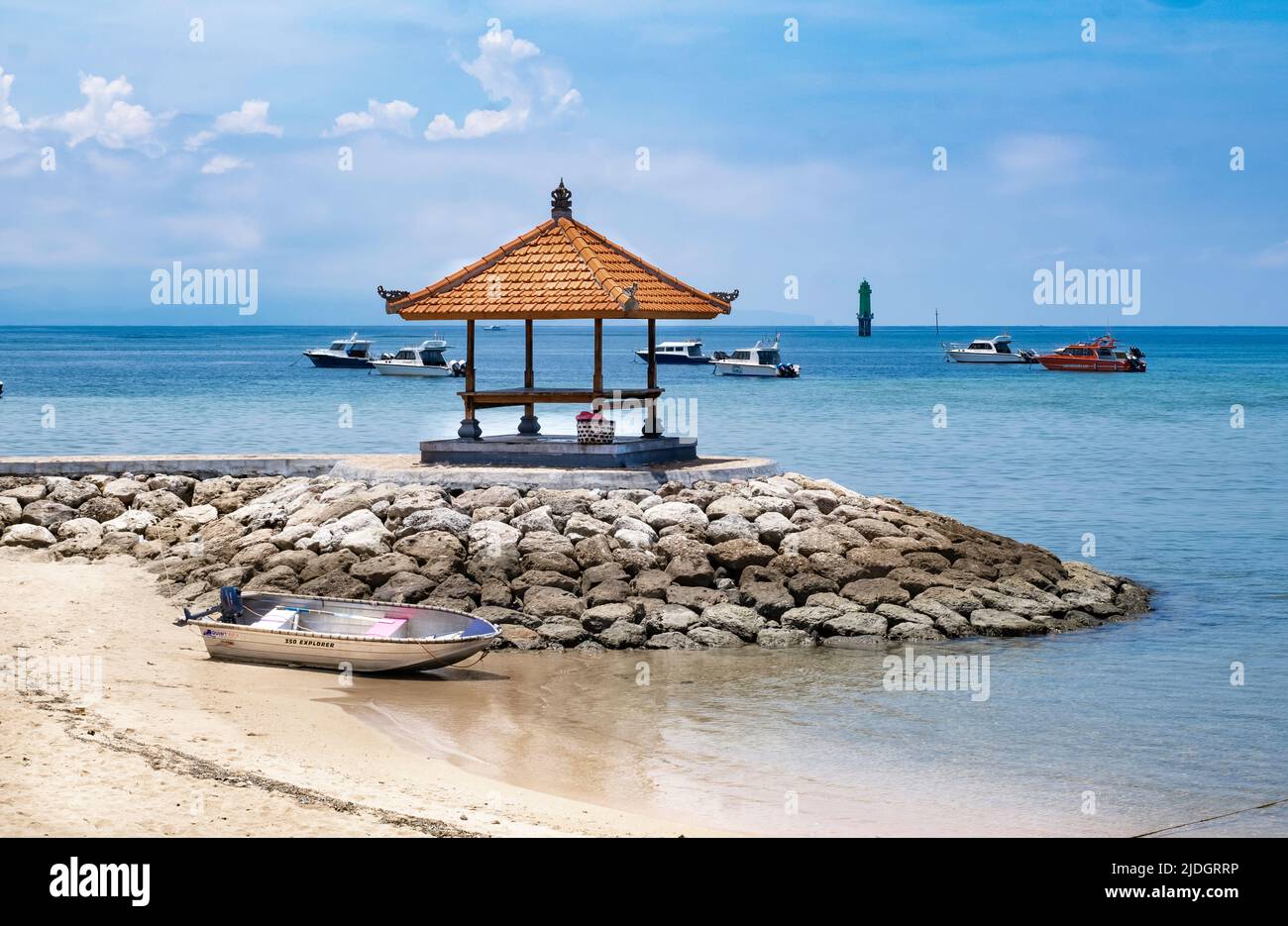 Holzpavillon mit Bambusdach auf Felsen getty am Rande der Strandküste in Bali, Indonesien, blauem Ozean und Booten, die in der Ferne schwimmen Stockfoto