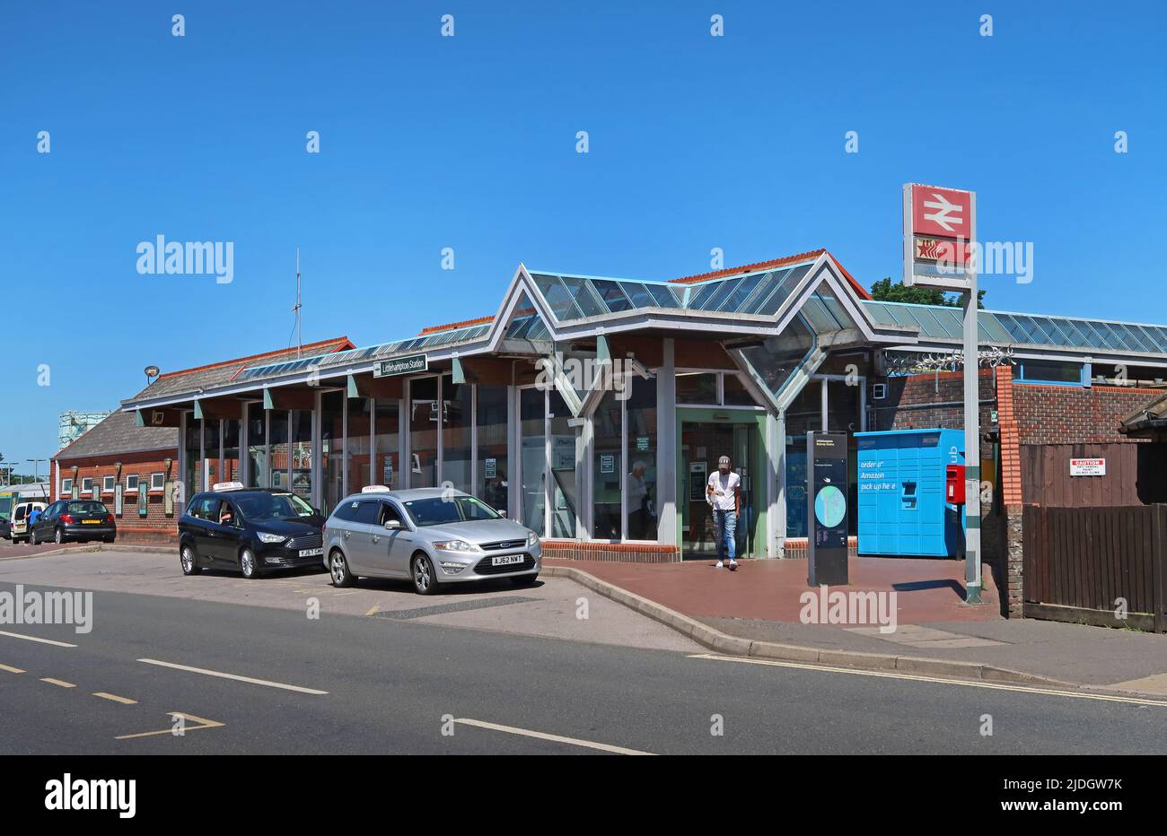 Littlempton Railway Station, West Sussex, Großbritannien. Terminus auf dem südlichen Netzwerk in diesem Küstenort. Zeigt das Eingangsgebäude und die Wartenden der Taxis. Stockfoto