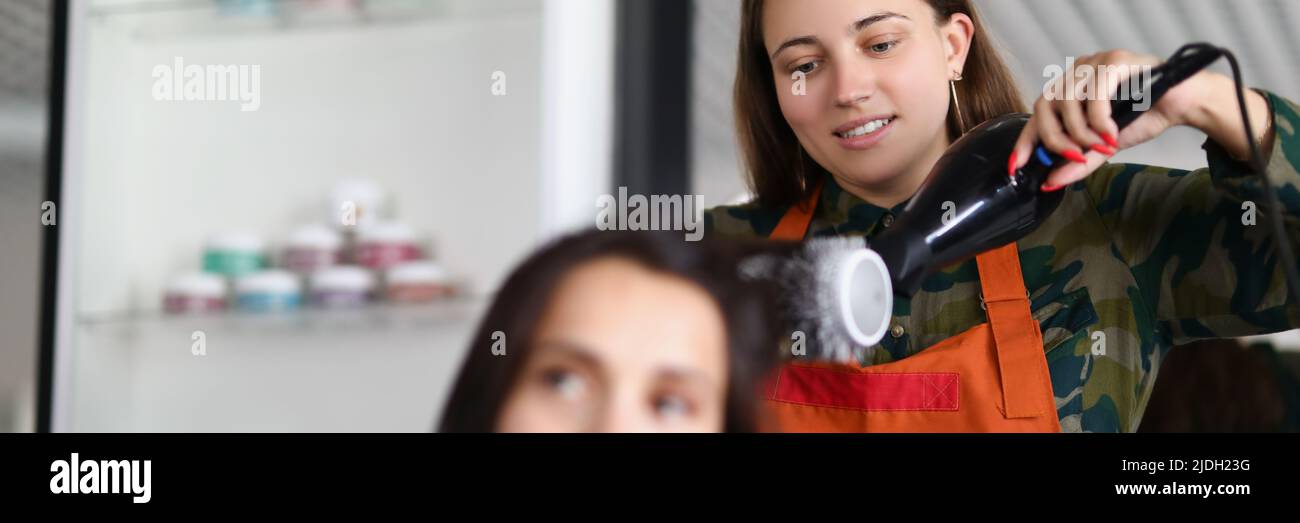 Lächelnder Friseur mit Haartrockner für die Behandlung mit Haaren und kreativ sein Stockfoto